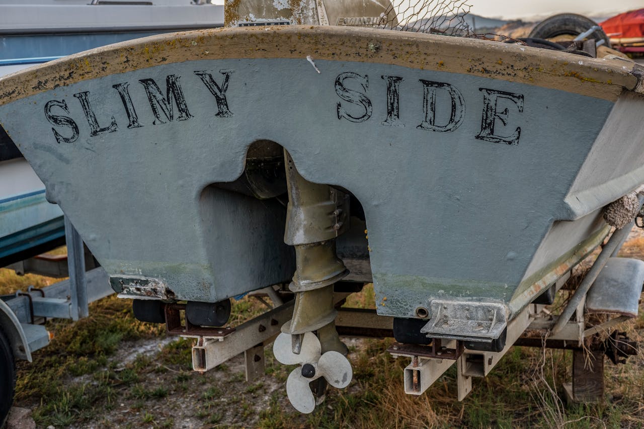 Close-up of a boat's stern showing 'Slimy Side' lettering and a rustic propeller.